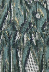 Tryckt tyg med en texturerad yta i nyanser av teal, grön och kräm. Innehåller ett lager på lager-mönster med abstrakta streck och subtila linjer.