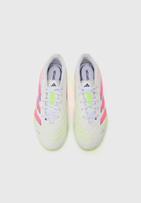 Zapatos de fútbol blancos con acentos en rosa neón y verde, que cuentan con una parte superior texturizada, cordones y un diseño a rayas distintivo.