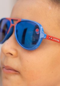 Blue and red Spider-Man sunglasses with oval lenses, textured frames, and character details on the arms. Reflective blue lenses.
