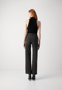 Top negro de canalé combinado con pantalones vaqueros de pierna ancha de talle alto en gris oscuro, con dos bolsillos traseros y un acabado liso. Botas negras con tacón.