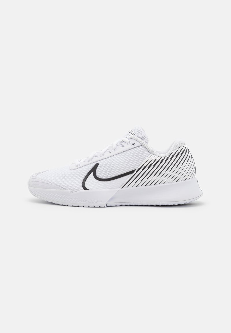 Basket de sport blanche en tissu en maille, avec un swoosh noir de Nike, une semelle texturée et un motif rayé sur le talon. Équipée de lacets et d'un col rembourré.