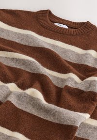 Maglione a righe marroni e grigie, realizzato in morbido tessuto a maglia, con scollo a girocollo a coste e una combinazione di toni caldi e neutri.