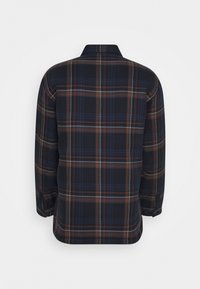 Långärmad flanellskjorta med ett rutigt mönster i blått, brunt och vitt, sedd bakifrån mot en enfärgad vit bakgrund.