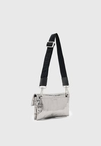 Borsa crossbody metallica argento con una forma strutturata, caratterizzata da una tracolla nera e dettagli in metallo argentato. Texture liscia con un leggero lucido.