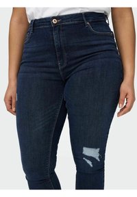 Mörkblå högmidjade jeans i denim, med en slitning på vänster lår och klassisk femficksmodell.