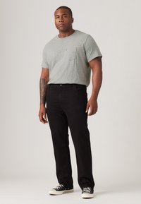 Grijze katoenen t-shirt met een borstzak, gecombineerd met zwarte denim jeans en zwarte sneakers met witte zolen. Eenvoudig, casual en veelzijdig.