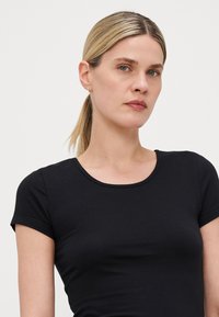 Schwarzes T-Shirt mit kurzen Ärmeln und Rundhalsausschnitt, aus weichem, dehnbarem Stoff gefertigt. Hat eine taillierte Passform und eine glatte Textur.