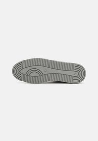 Semelle d'une chaussure grise avec un motif de traction rainuré et des marquages de taille 42 et FP visibles sur un fond uni.