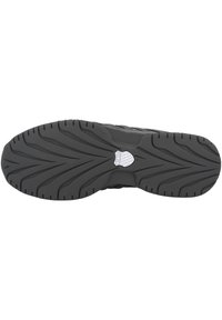 Schwarze Sneaker-Sohle mit einer strukturierten GummOberfläche und tiefen Rillen für besseren Halt sowie einem Logo in der Mitte. Elegantes Design für Stabilität.