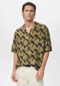 Chemise pour homme à manches courtes de couleur olive avec un motif abstrait noir, présentant une coupe décontractée, un col boutonné et une texture de tissu lisse.