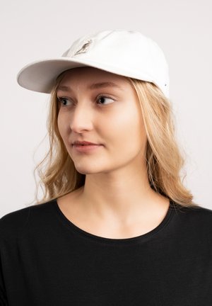 Cappellino bianco in cotone con visiera curva e logo ricamato sul fronte; indossato con una maglietta nera, caratterizzata da una consistenza morbida e un design casual.