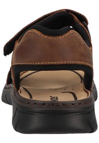 Brown leather sandal with a textured black rubber sole, adjustable straps, open back design, and a cushioned footbed.