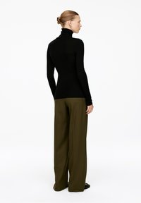 Black turtleneck top with long sleeves paired with high-waisted, wide-leg olive-green trousers. Smooth texture, fitted silhouette.