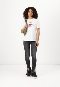 Balta medvilninė marškinėliai su užrašu "HOOP! JEANS!" raudona ir mėlyna spalvomis, derinama su tamsiai pilkais aptemptais džinsais su šoninėmis sklendėmis. Juodi sportbačiai.