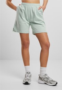 Light green, elastic-waist shorts with side pockets; soft cotton material; knee-length cut with side slits for ease of movement.