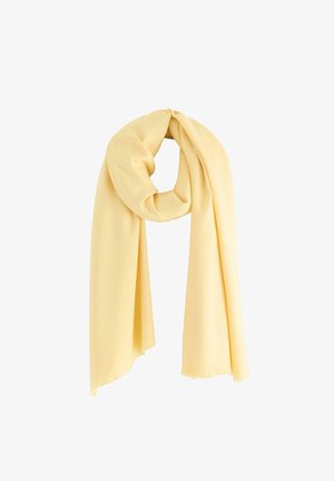 Žlutý šátek vyrobený z jemného materiálu, poskládaný tak, aby předváděl svou hladkou strukturu, s třepivými okraji, visící v kruhu.