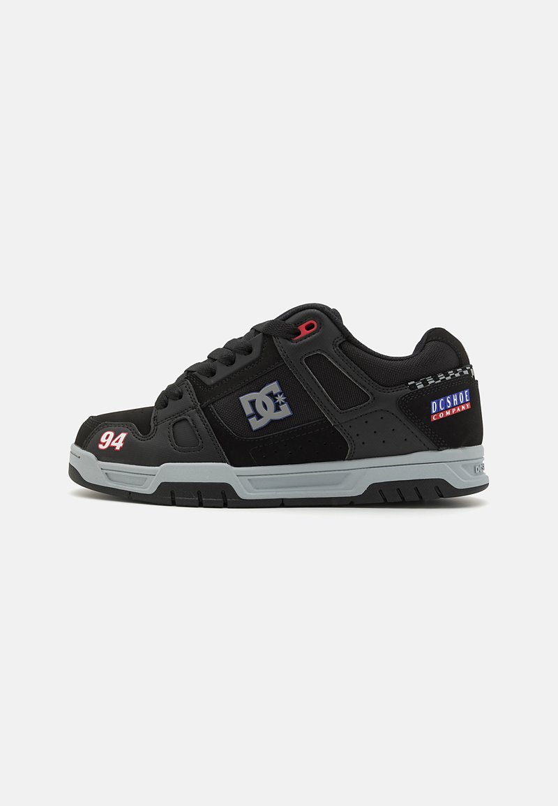 Sapatos de skate pretos com sola cinza, apresentando materiais em malha e têxtil. Os detalhes incluem logos em vermelho e azul, com "94" impresso em vermelho.
