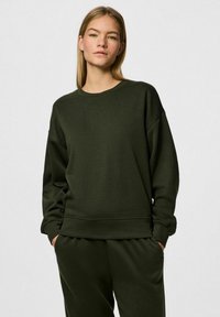 Felpa verde scuro con vestibilità comoda, scollo rotondo e polsini a coste. Realizzata in tessuto morbido, presenta un design semplice e minimalista.
