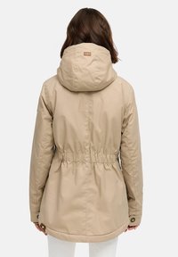Beige letvægtsjakke med hætte, indsnørret talje og snorstrop. Har en glat overflade og knapdetaljer ved ærmerne.