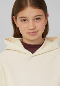 Crème-kleurige hoodie met een zachte textuur, voorzien van een trekkoordcapuchon en een gelaagd effect over een bordeauxrood shirt. Ontspannen pasvorm, minimalistisch ontwerp.