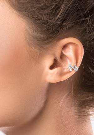 Strieborný ušný šperk v tvare vlny so svetlými rhinestonmi. Hladký povrch a jemný lesk, umiestnený na hornej časti ucha.