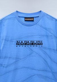 T-shirt in cotone blu con un delicato motivo a onde, colletto rotondo e logo "NAPAPIJRI geographic" in nero al centro.