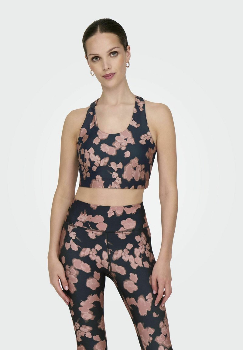 Vojska sportski grudnjak i tajice set s ružičastim cvjetnim uzorkom, izrađen od rastezljivog materijala s glatkom teksturom.
