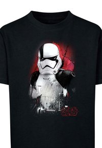 Černé bavlněné tričko s grafikou Stormtroopera na červeném a šedém pozadí s polévkovou barvou a textem "Star Wars" v červené.