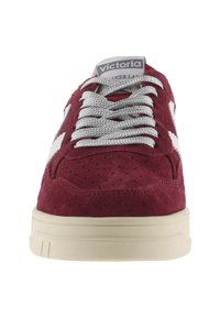 Sneaker in suede bordeaux con dettagli perforati, accenti bianchi e lacci grigi. Presenta una suola in gomma e un'etichetta con il marchio sulla linguetta.