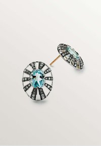 Los pendientes en plata y negro presentan una prominente piedra de aquamarina, con un diseño de estallido solar de líneas alternas y pequeñas piedras de acento.