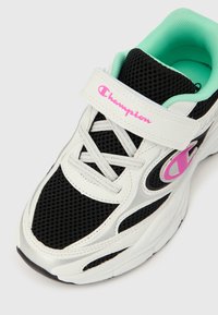 Λευκό και μαύρο αθλητικό παπούτσι με ροζ λογότυπο Champion, με εσωτερική επένδυση σε μέντα, γκρι κορδόνια και velcro λουράκι στο πάνω μέρος.