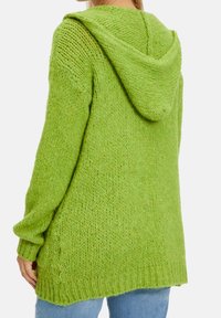 Maglione verde lavorato a maglia con cappuccio, taglio morbido, maniche lunghe e polsini a coste. Presenta un motivo testurizzato e cuciture delle spalle abbassate.