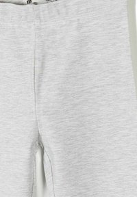 Svjetlosive hlače od mekane tkanine sa krupnim planom prednjeg središnjeg šava i pojasa, prikazujući teksturu i detalje šavova.