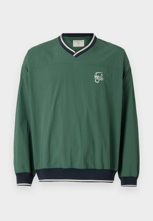 Grüner Pullover mit V-Ausschnitt, kontrastierendem marineblauem Rippkragen und elastischen Bündchen. Verfügt über ein kleines weißes Logo auf der Brust. Leichtes Material.