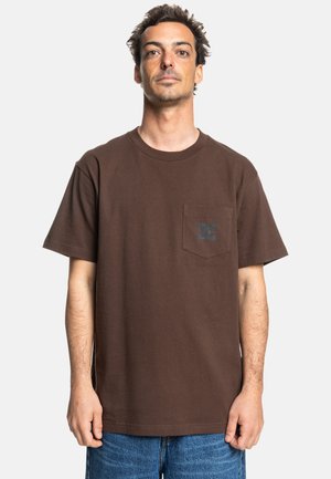 Camiseta corta de manga corta color marrón, hecha de algodón, con un bolsillo en el pecho y un estampado de logo, de corte relajado y textura suave.