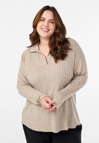 Bežani pleteni pulover s teksturiranim uzorkom, dugim rukavima i ovratnikom. Ima ležeran kroj i razdvajanja sa strane na rubu.