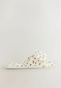 Papučky s kvetinovým vzorom z mäkkej, textúrovanej tkaniny. Krémové pozadie s malými viacfarebnými kvetmi a dvoma vystupujúcimi kvetinovými ozdobami na vrchu.