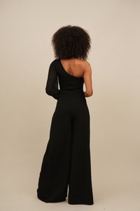 Svart jumpsuit med en skulderdesign; lang erm på den ene siden, avslappet passform, brede bukseben og glatt tekstur.