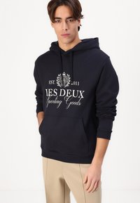Felpa con cappuccio blu navy, dotata di tasca anteriore, con testo e logo bianchi e polsini a costine. Tessuto in cotone morbido.