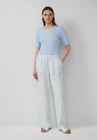 Top a righe azzurro chiaro con maniche corte abbinato a pantaloni a gamba larga a strisce blu chiaro e bianche, con vita elastica e tasche.