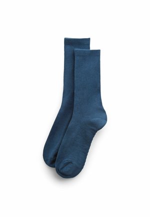 Par de calcetines lisos azul oscuro hasta la mitad de la pantorrilla con puños acanalados, colocados planos sobre un fondo blanco.