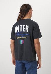 Schwarzes Baumwoll-T-Shirt mit großem weißen und blauen Text "INTER Nerazzurri" auf dem Rücken, ergänzt durch ein Wappen-Logo und "20" darunter.