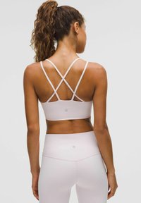 Gaiši rozā sporta krūšturis ar krustveida siksnām, teksturēta auduma un ar logotipa detaļu. Saskaņots ar atbilstošām augsto jostasvītru legingu.