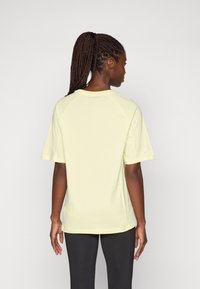 Lichtgele T-shirt met korte mouwen en een relaxte pasvorm, raglanmouwen en zachte stof. Het heeft een ronde halslijn en een afgeronde zoom.