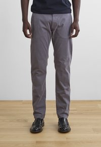 Gray cotton chinos with a straight leg fit, featuring a smooth texture and side pockets, paired with black leather loafers.