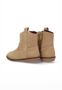Botas de tobillo de ante color marrón con cremallera lateral, lengüeta para tirar y detalles de costura en forma de diamante en los lados. Forro interior suave y suela plana.