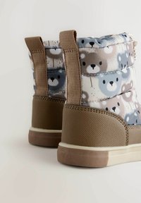Braun- und grau gemusterte Stiefel mit Bärenmotiven, weichem gepolstertem Obermaterial, flexibler Sohle und Stoffzuglaschen für ein einfaches Anziehen.
