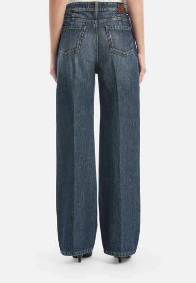 Plašas zilo denim džinsus ar augstu jostasvietu, tumšā mazgājumā, ar aizmugures kabatām un ādas zīmola uzkodu pie jostasvietas.