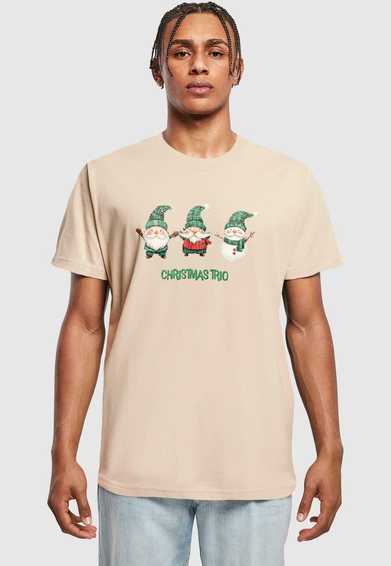 Beige bomulds t-shirt med et "Juletre" grafik. Tre nisser i grønne og ternede hatte, med accenter af rød og hvid.
