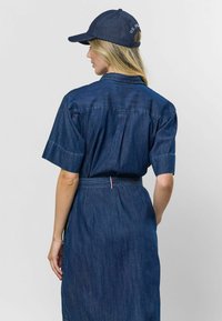 Džínová košeľová šaty s krátkymi rukávmi, sťahovaným pásom a rozparkom v zadnej časti. Má tmavomodrú farbu a zodpovedajúcu džínovú čiapku.